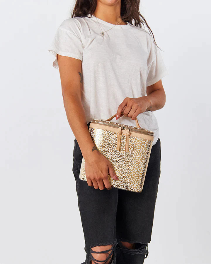 Woman wearing a white t-shirt and ripped black jeans carrying a glitter travel tote.