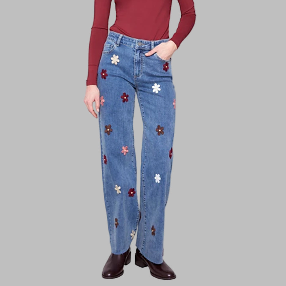 Blue jeans with floral patches worn by a person on a white background