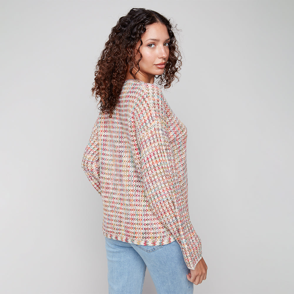 Woman wearing a patterned blouse and light blue jeans against a plain background