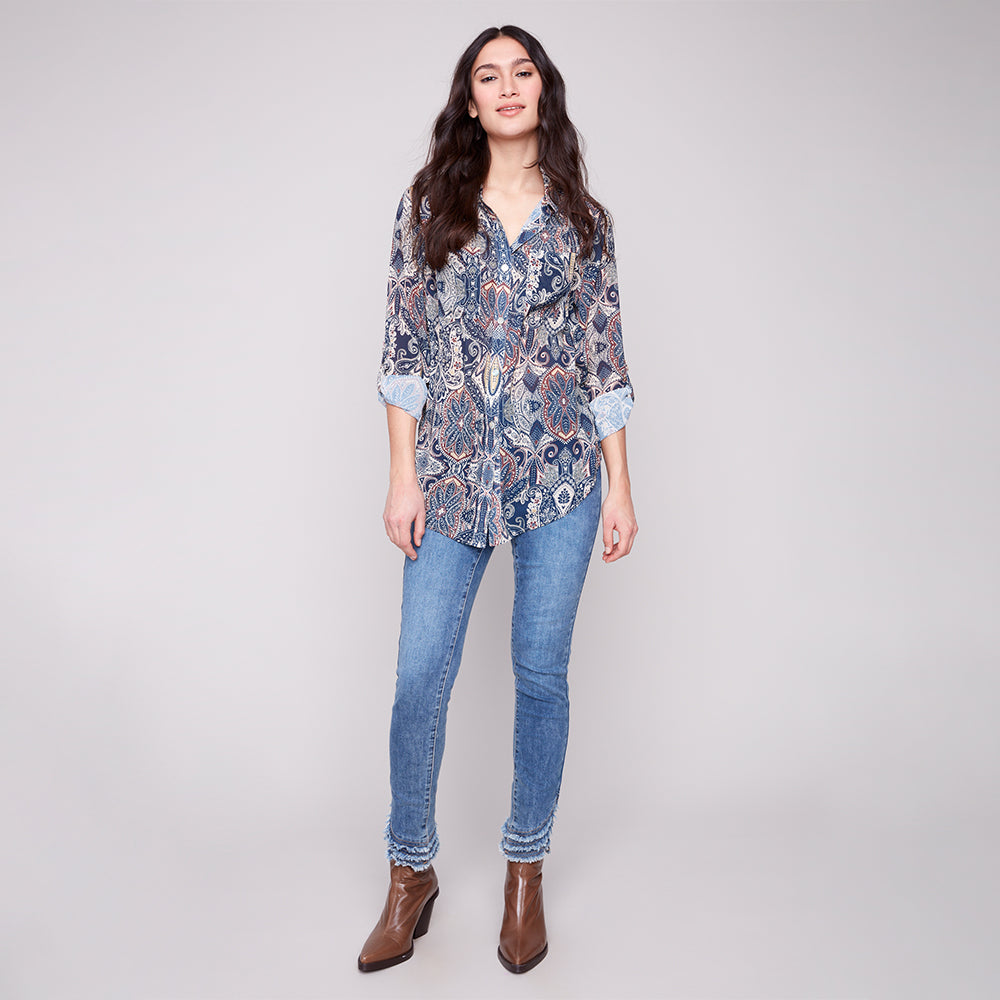 Woman wearing a patterned blouse and blue jeans on a white background