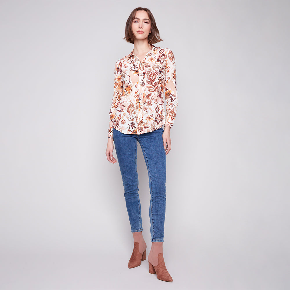 Woman wearing a floral blouse and blue jeans on a gray background