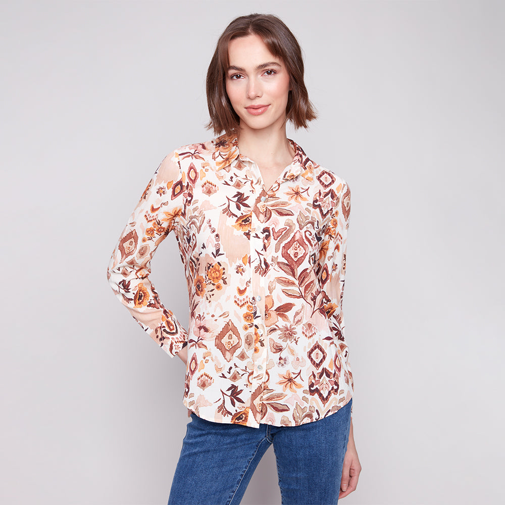 Woman wearing a floral patterned blouse against a plain background