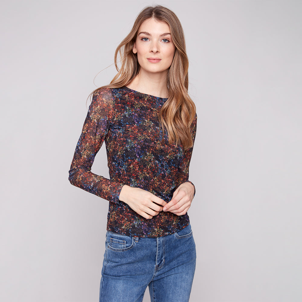Woman wearing a floral long-sleeve top and jeans on a plain background