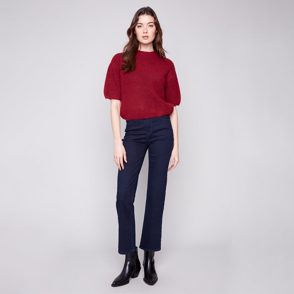 Woman wearing a red sweater and navy pants on a white background