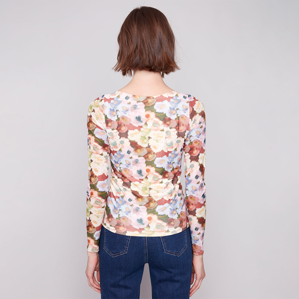 Person wearing a floral long-sleeve top and blue jeans on a plain background