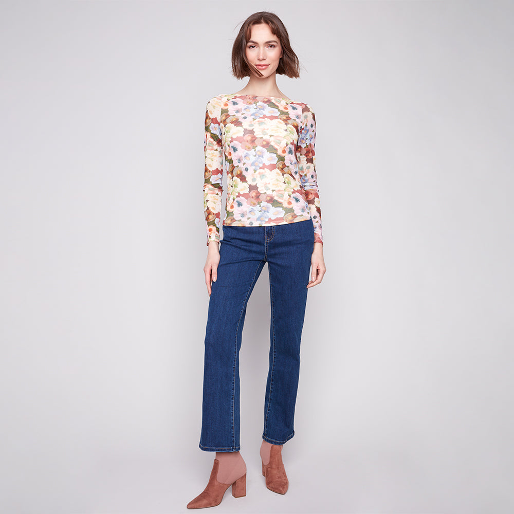 Woman wearing a floral top and blue jeans on a plain background