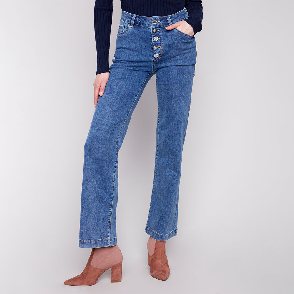 Person wearing blue jeans with a button fly on a white background