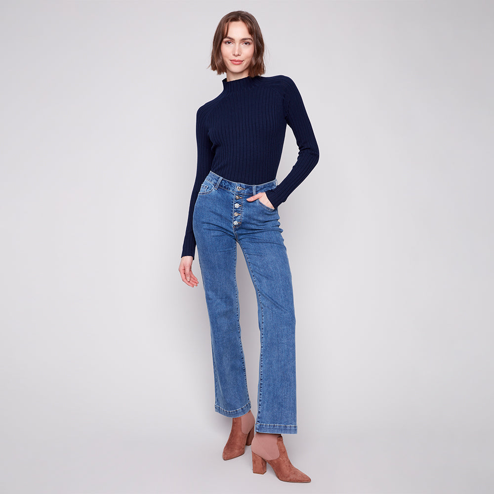 Woman wearing a navy sweater and blue jeans on a white background