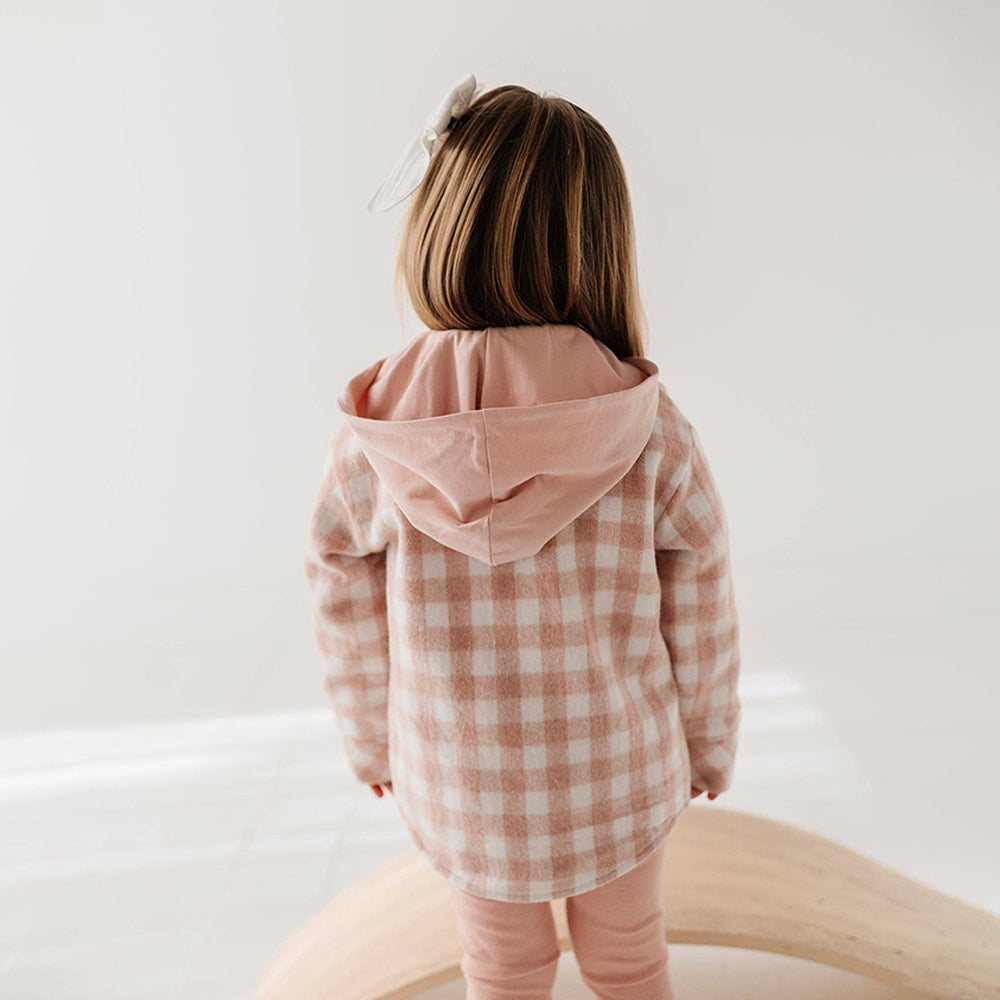 Child wearing a pink checkered jacket on a white background