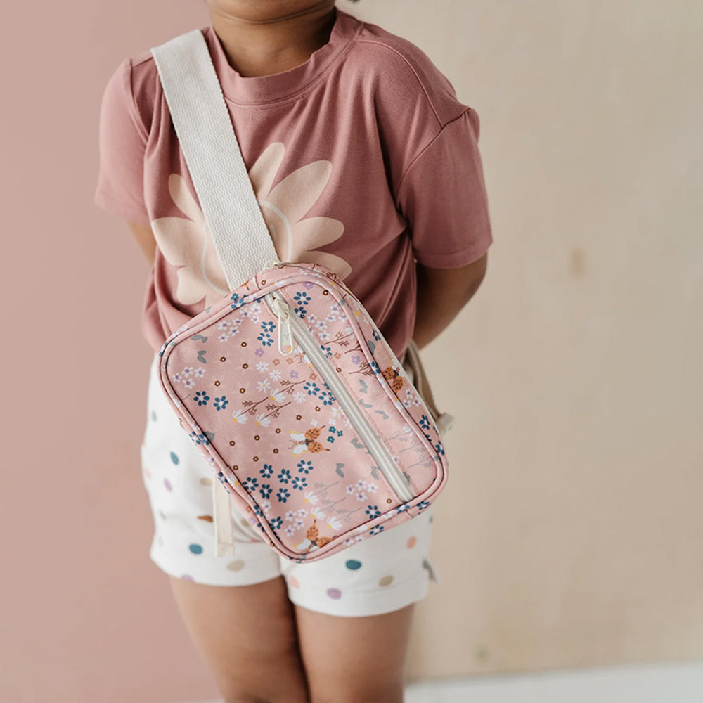 Person wearing a pink floral crossbody bag against a plain background