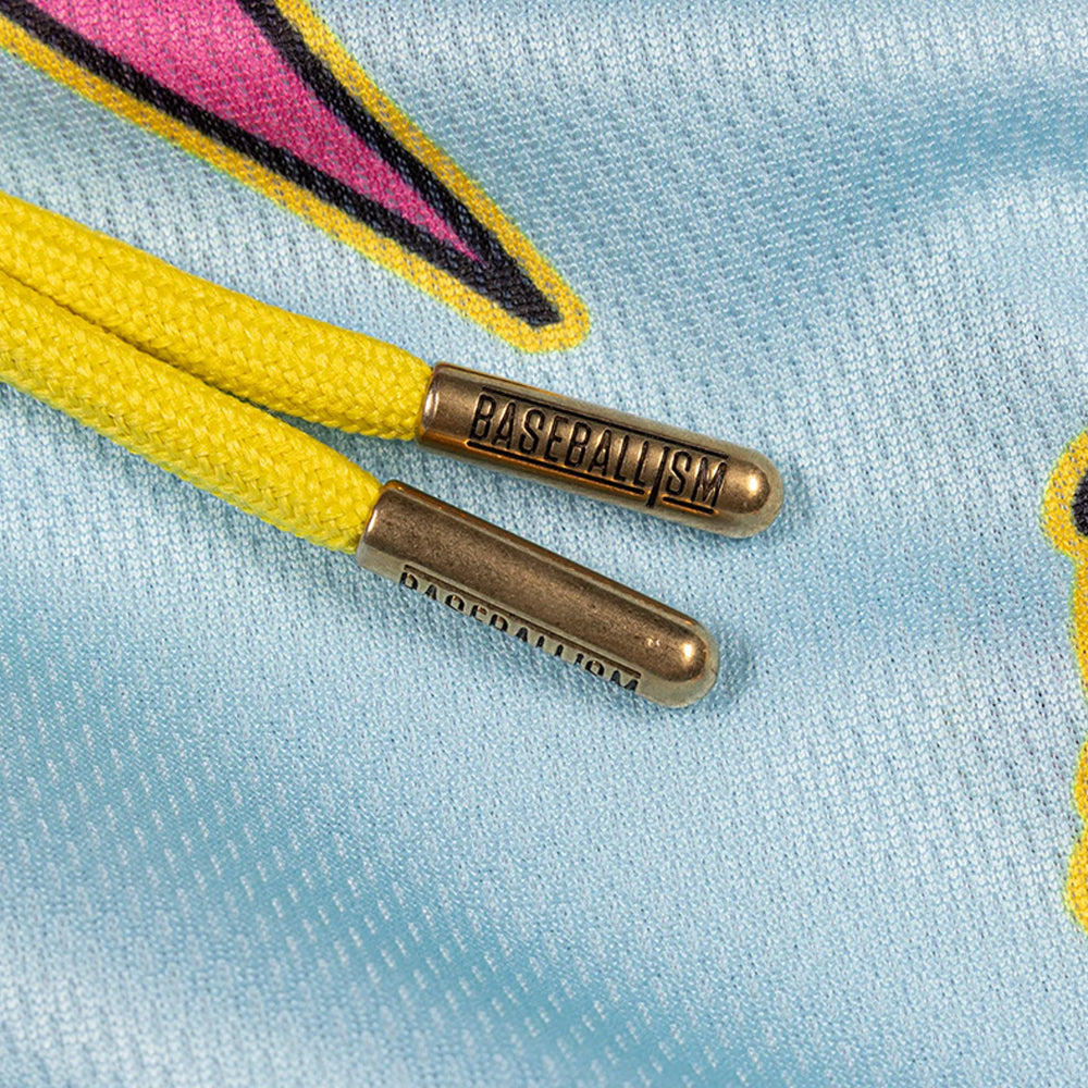 Close-up of yellow laces threaded through a light blue mesh garment, with metallic bronze lace tips engraved with the word 'BASEBALL'.