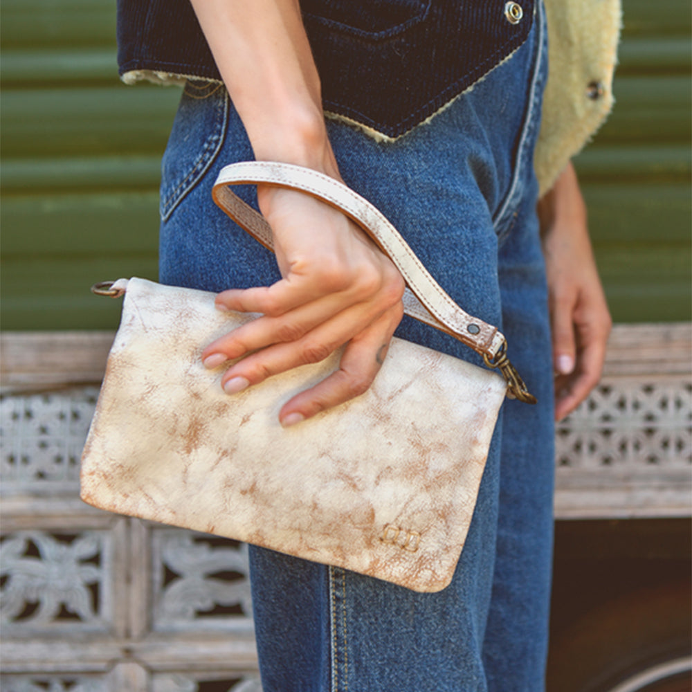 A person holding a beige Bed Stu Cadence- Nectar Lux crossbody handbag.