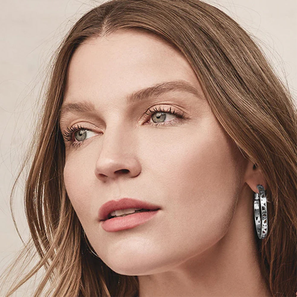Close-up of a woman wearing hoop earrings with a neutral background
