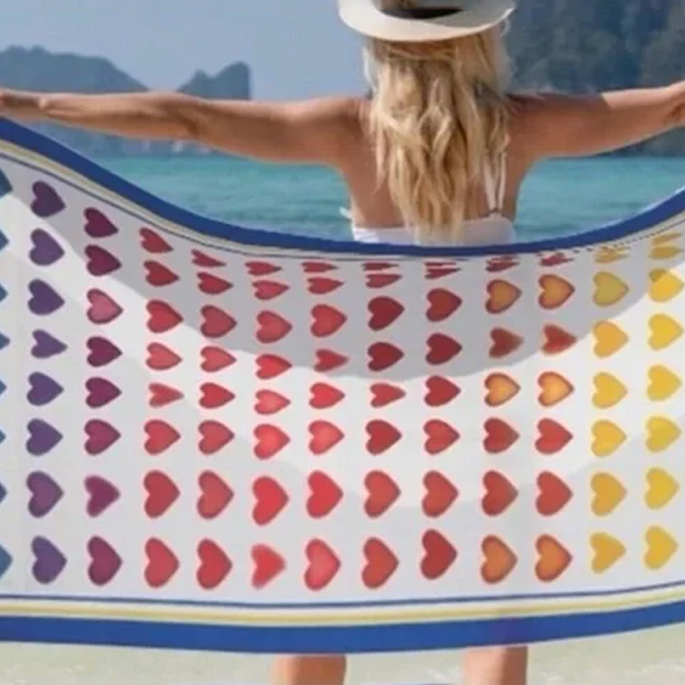 Person holding a colorful heart-patterned towel with a scenic background