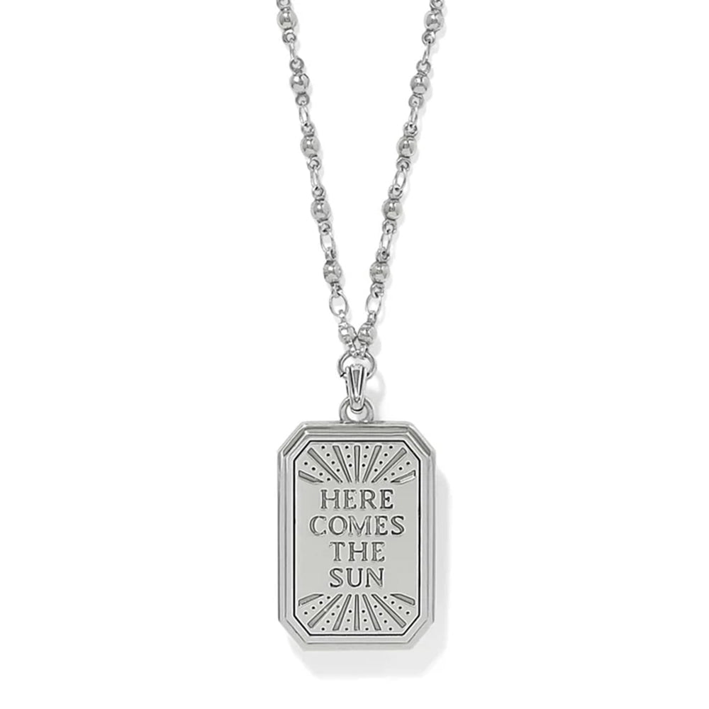 A silver pendant necklace featuring a rectangular tag-style pendant with the engraved text 'HERE COMES THE SUN' and a sunburst design, shown on a white background.