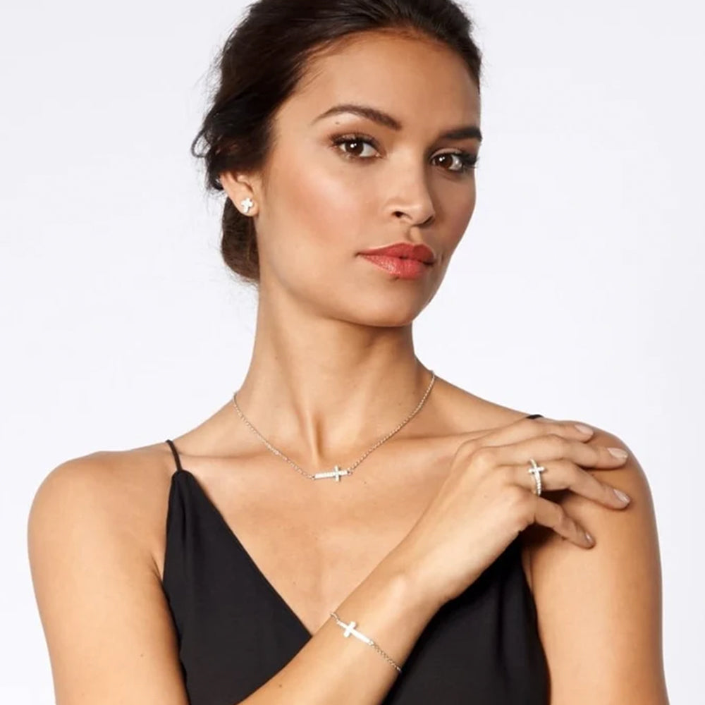 Woman wearing a necklace, ring, and bracelet on a plain background