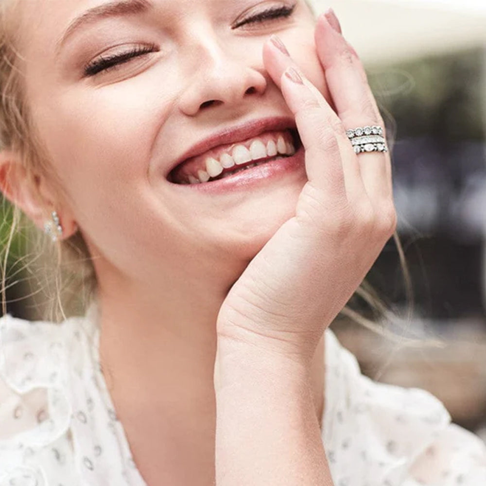 Woman with a smile, wearing rings and earrings, with a blurred background