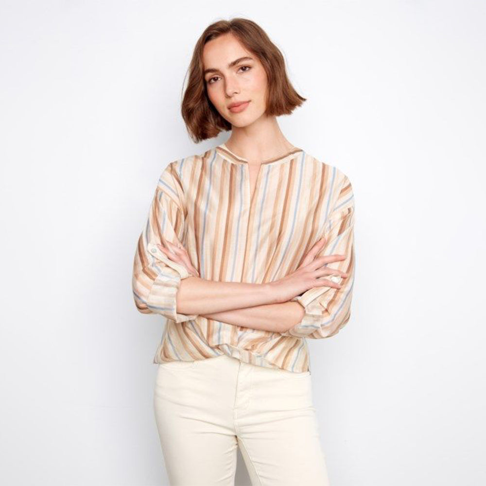 Woman wearing a striped shirt and white pants against a plain background