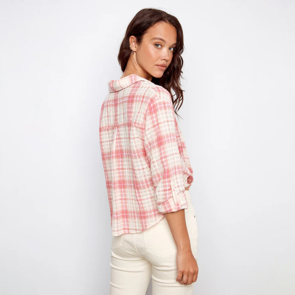Woman wearing a pink and white plaid shirt against a white background