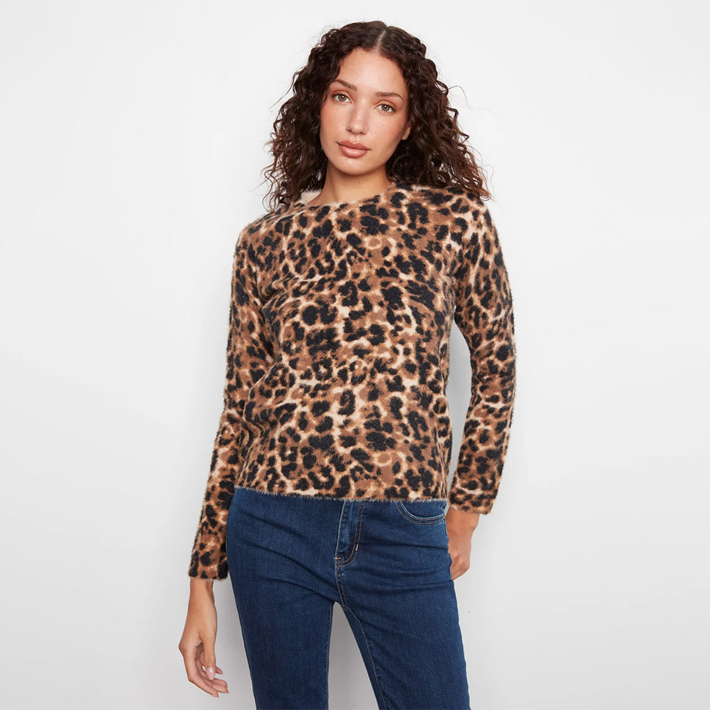 A woman modeling a long-sleeve leopard print top with dark blue jeans against a plain white background.