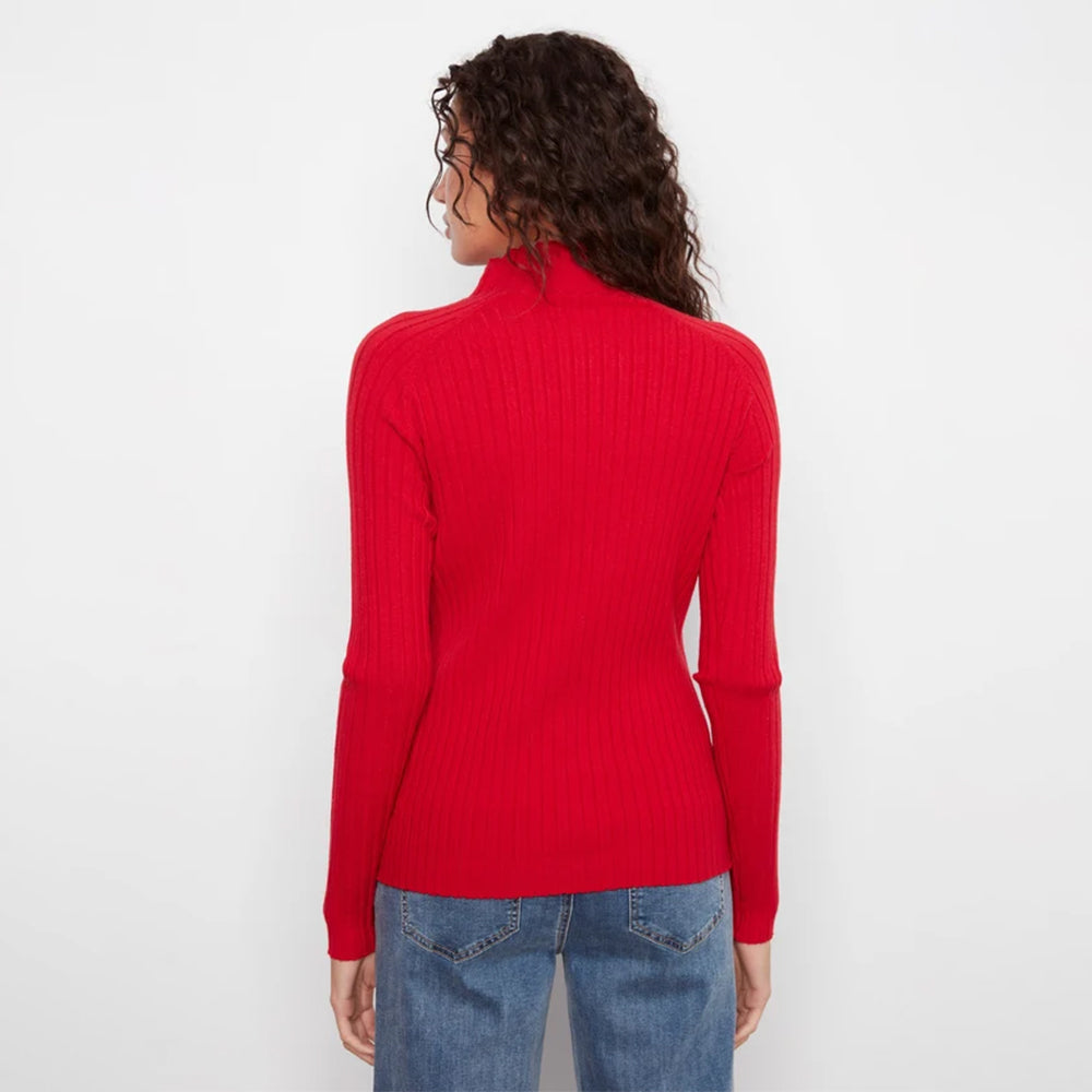 A woman viewed from the back wearing a bright red ribbed turtleneck sweater and blue jeans against a plain white background.
