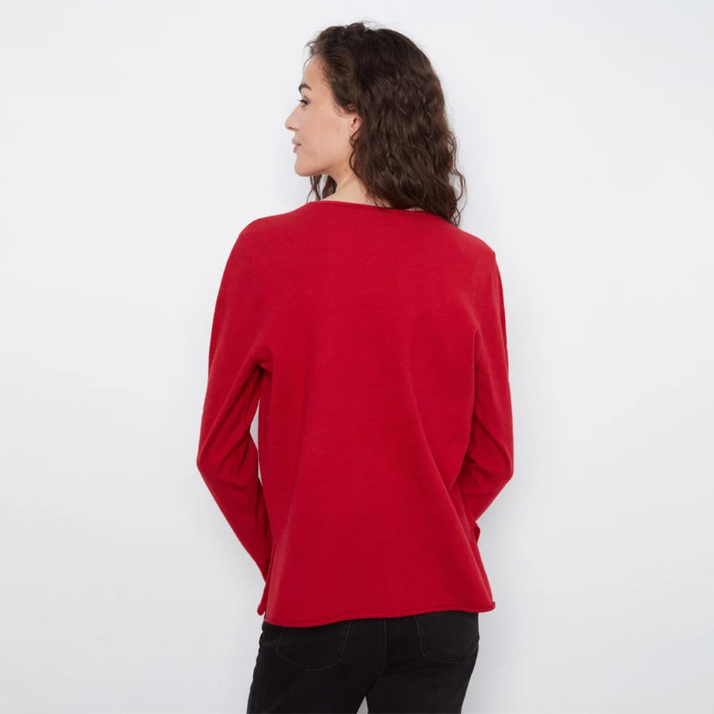 A woman with dark curly hair is shown from the back wearing a bright red long-sleeve top and black pants against a plain white background.