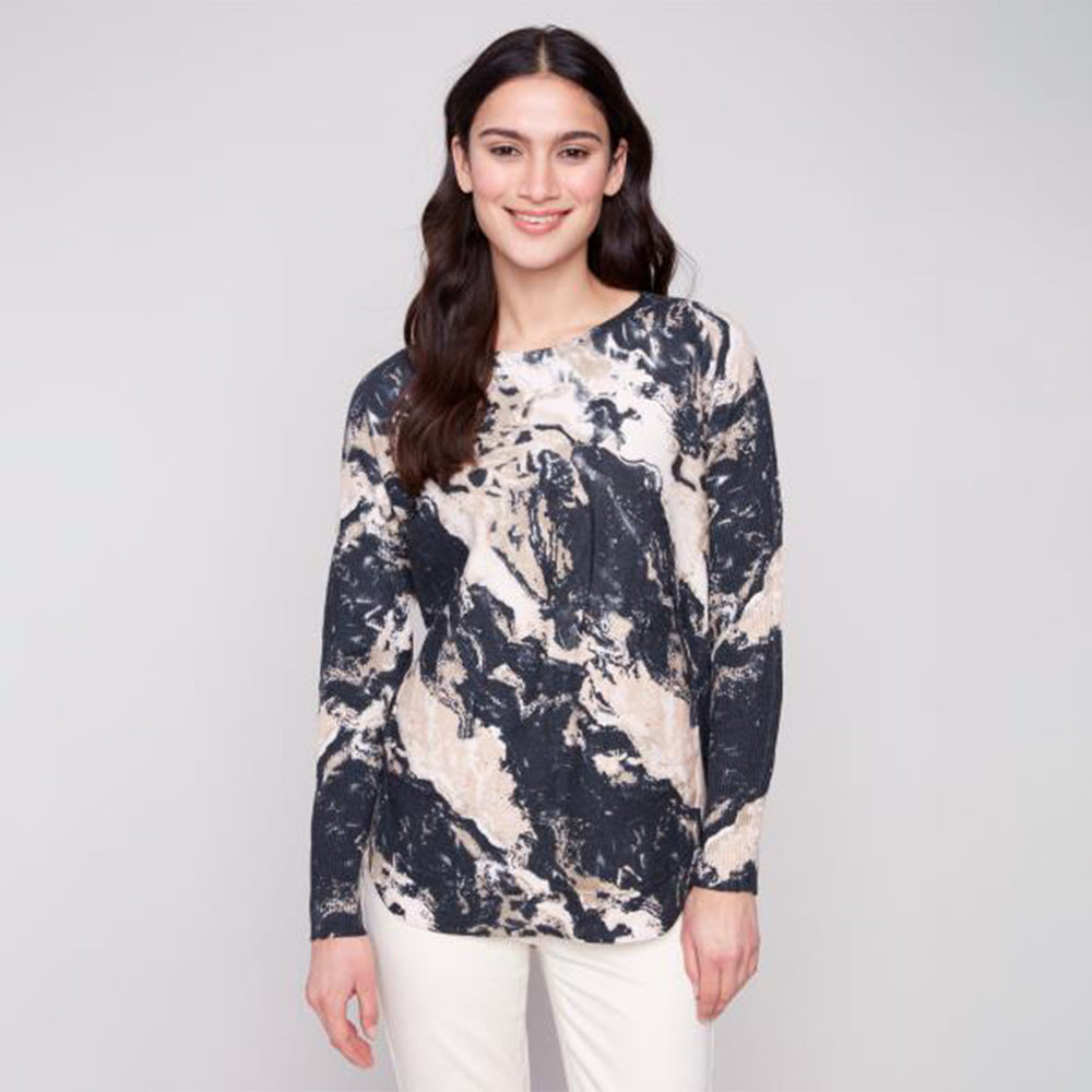 Woman wearing a patterned long-sleeve top against a plain background