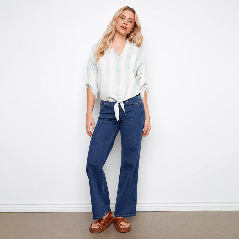 Woman wearing a striped shirt and blue jeans against a white background