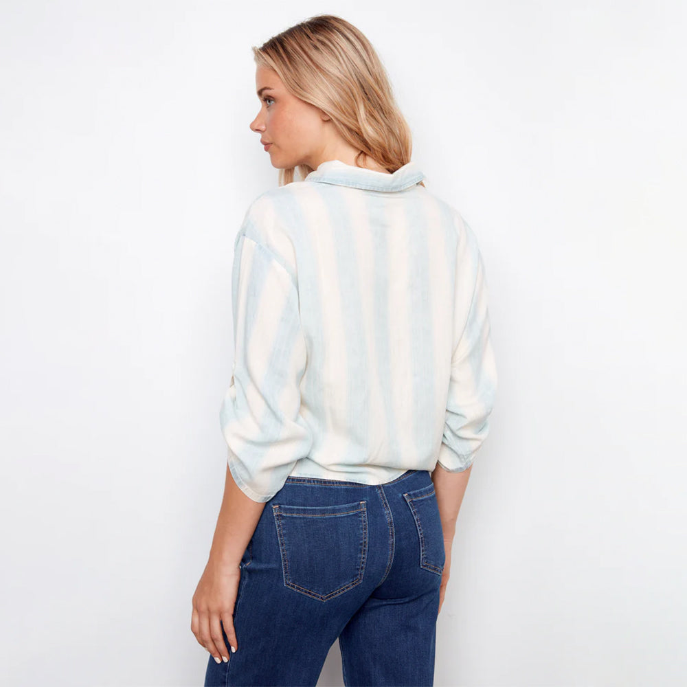 Woman wearing a tie-dye shirt and blue jeans against a white background