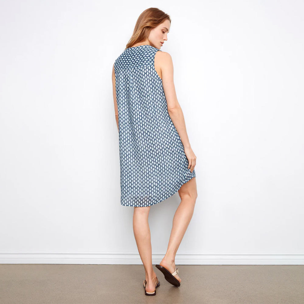 Woman wearing a blue patterned dress against a white wall