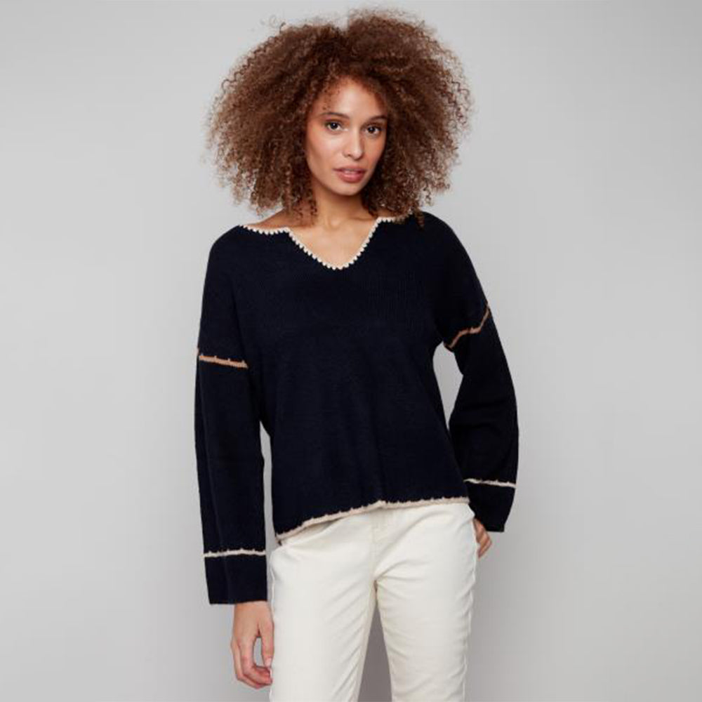 Woman wearing a black sweater with white trim against a gray background