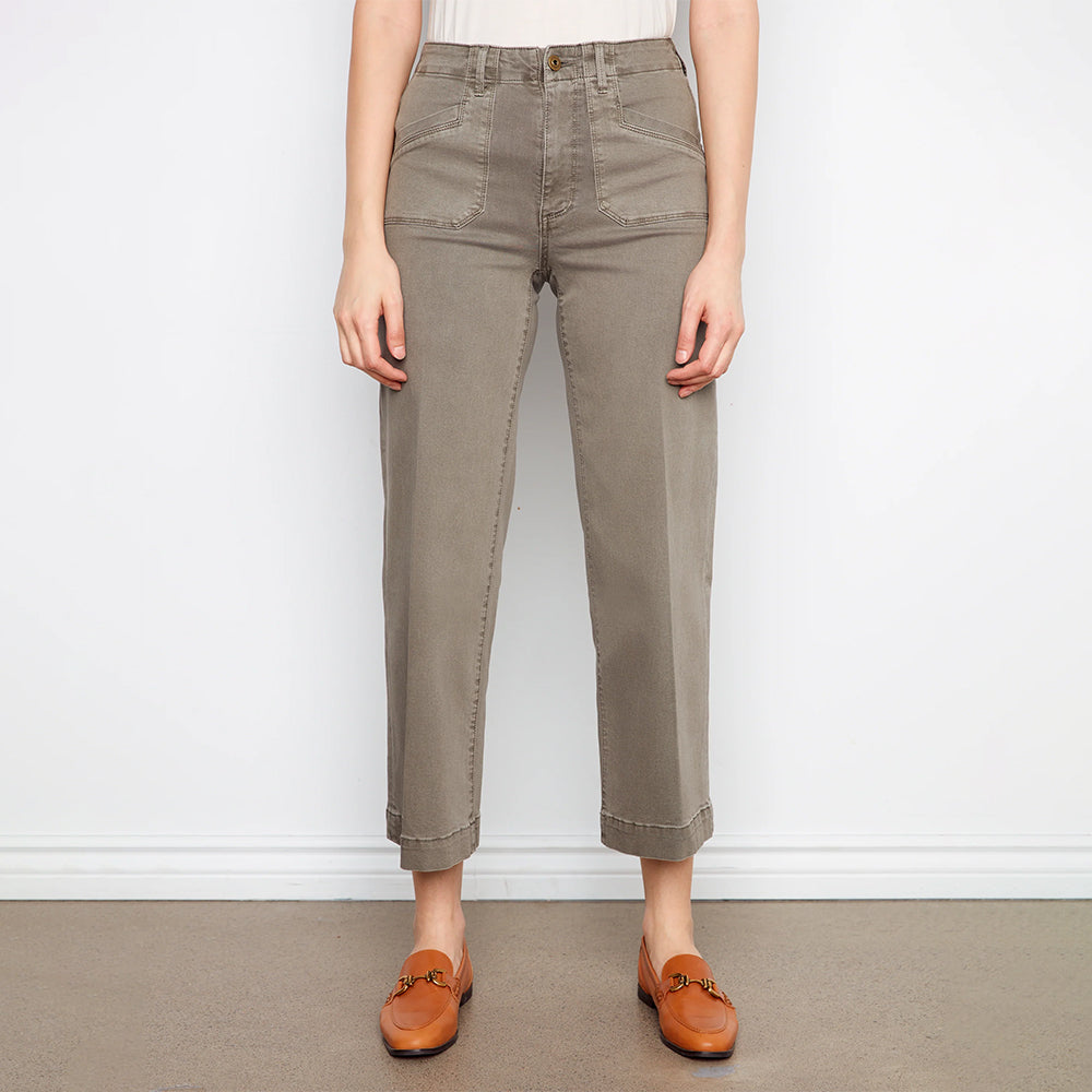 Person wearing beige pants and brown shoes on a plain background