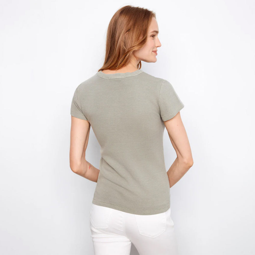 Woman wearing a light green t-shirt and white pants on a plain background