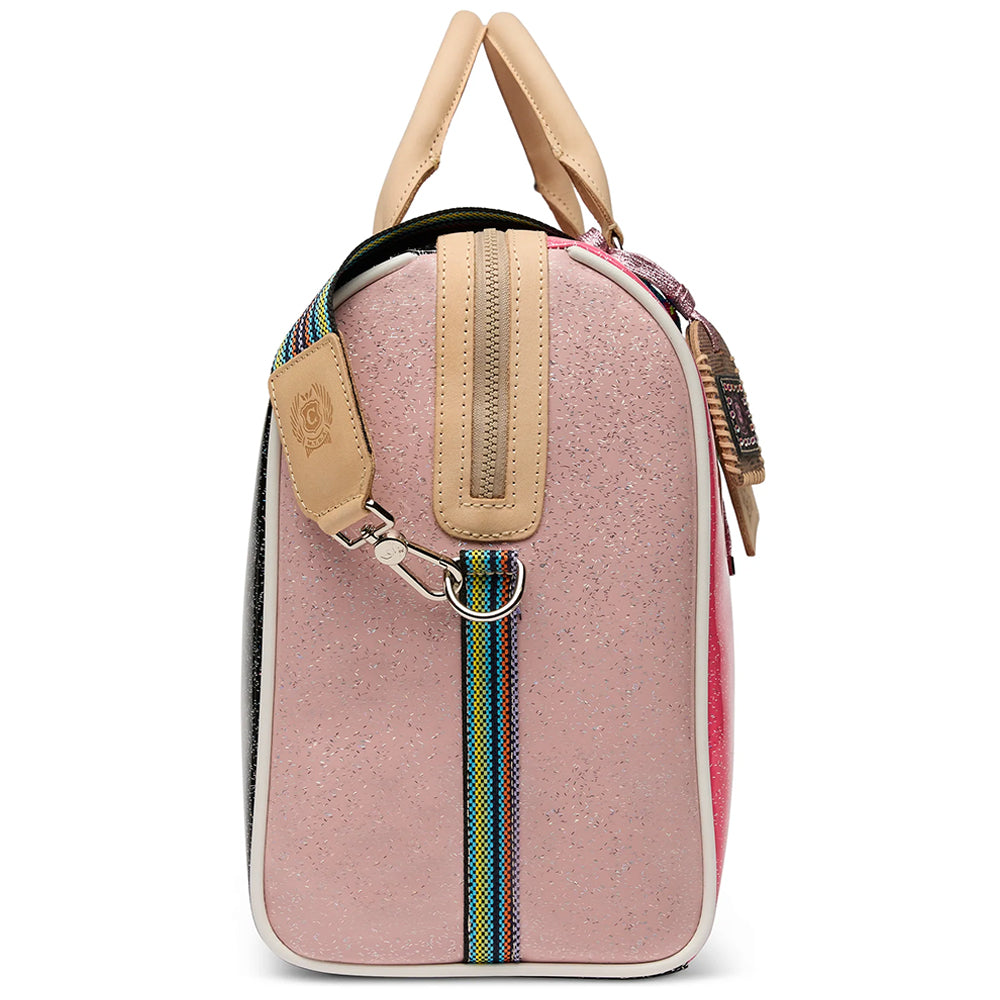 A structured pink jet setter bag with beige leather handles and trim, featuring a colorful woven strap and a silver metal clasp, shown against a plain white background.