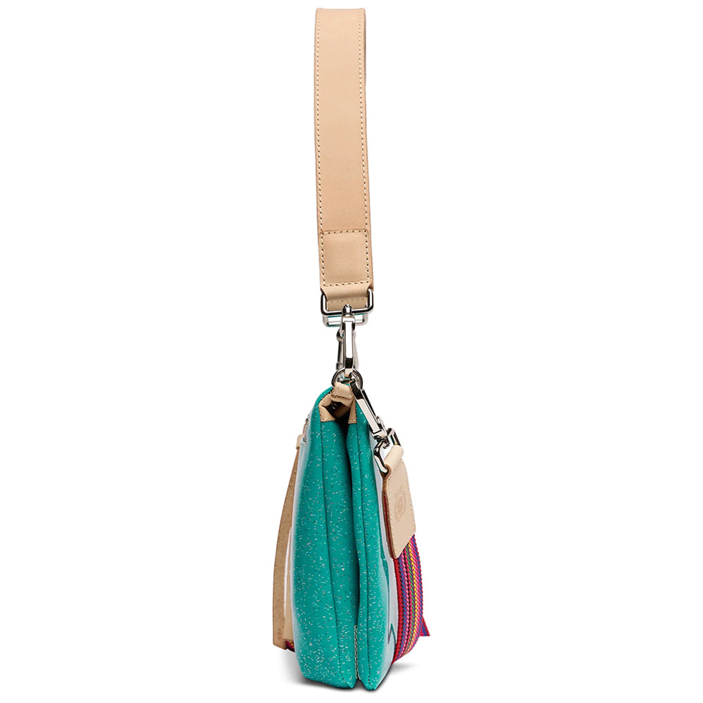 A side profile view of a handbag with a turquoise glittery body, beige leather strap and trim, and a pink and blue patterned accent panel, shown on a white background.