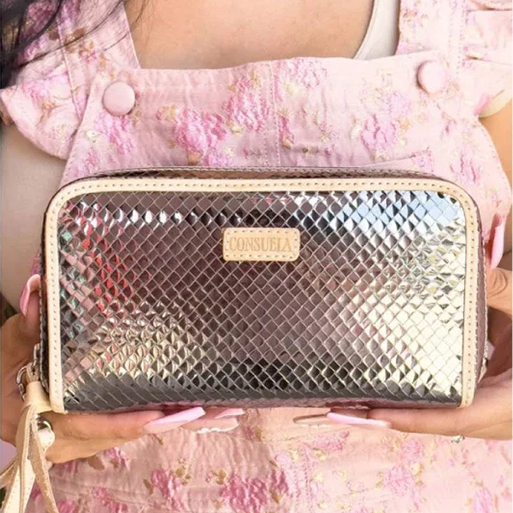 Silver patterned handbag held by a person wearing a pink floral dress.