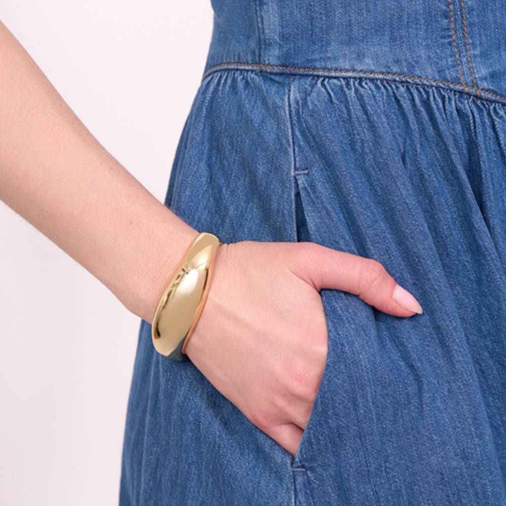 Gold bracelet on a wrist with a blue denim dress