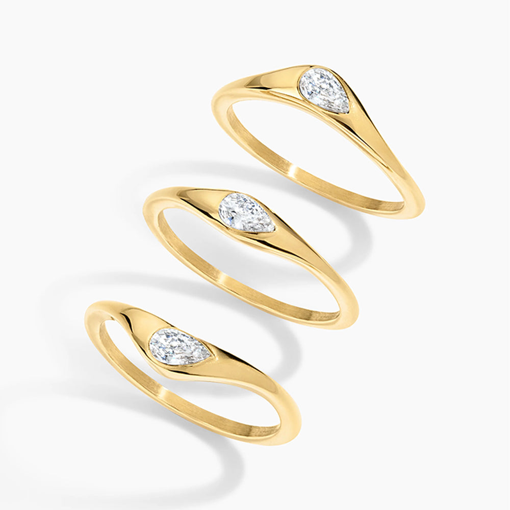 Three gold rings with marquise-cut clear gemstones, arranged diagonally on a clean white background.