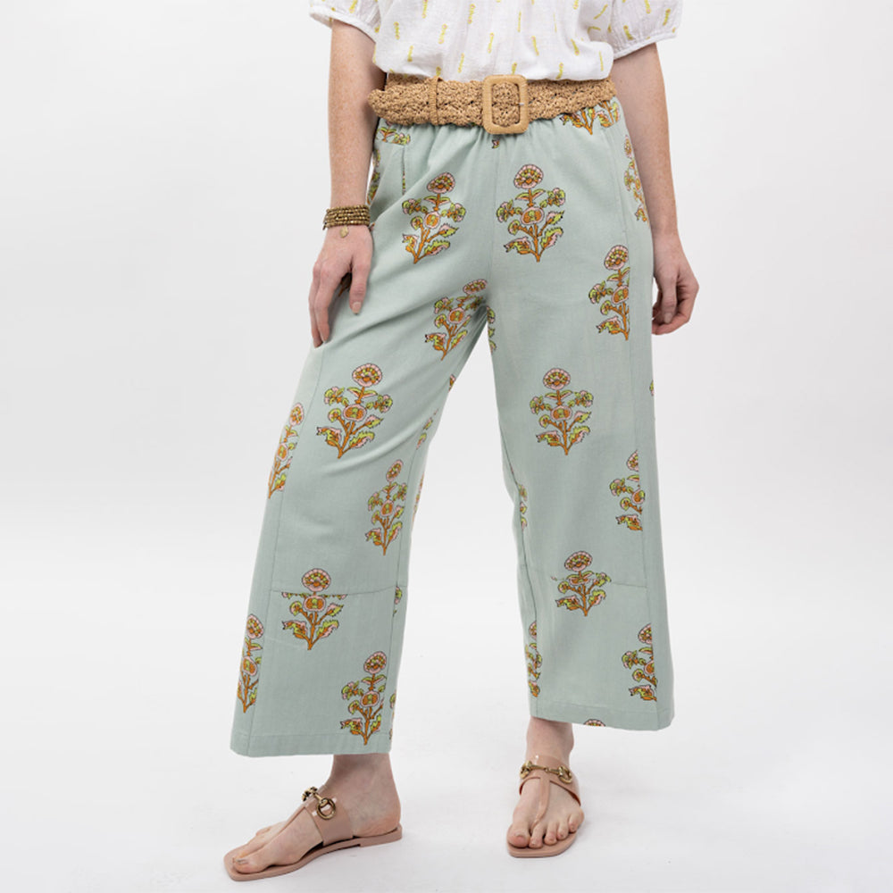 Person wearing light blue pants with floral patterns on a white background