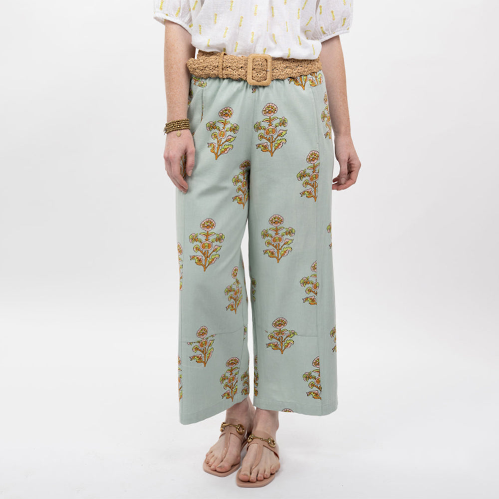 Person wearing light blue pants with floral patterns and a white top on a white background