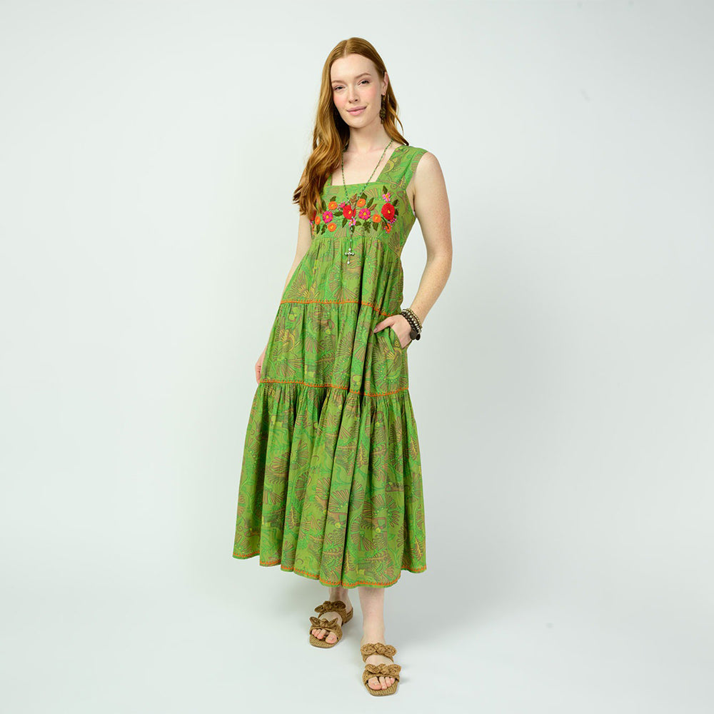 Woman wearing a green dress with floral embroidery on a white background