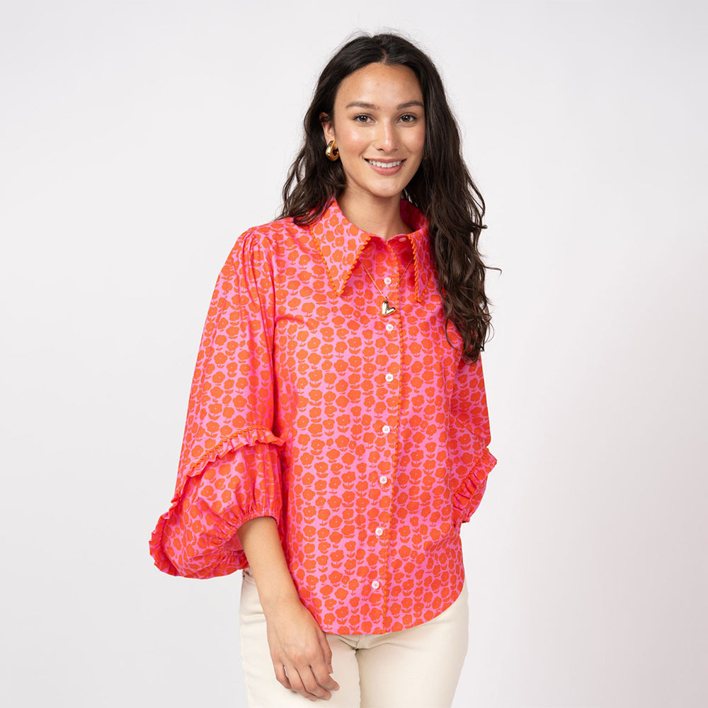 Woman wearing a bright pink patterned blouse on a white background