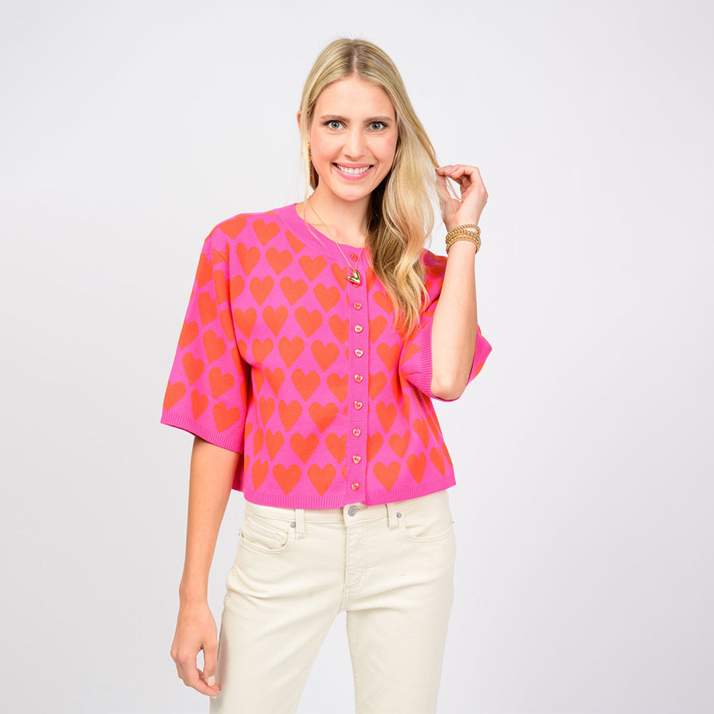 Woman wearing a pink blouse with red heart patterns on a white background