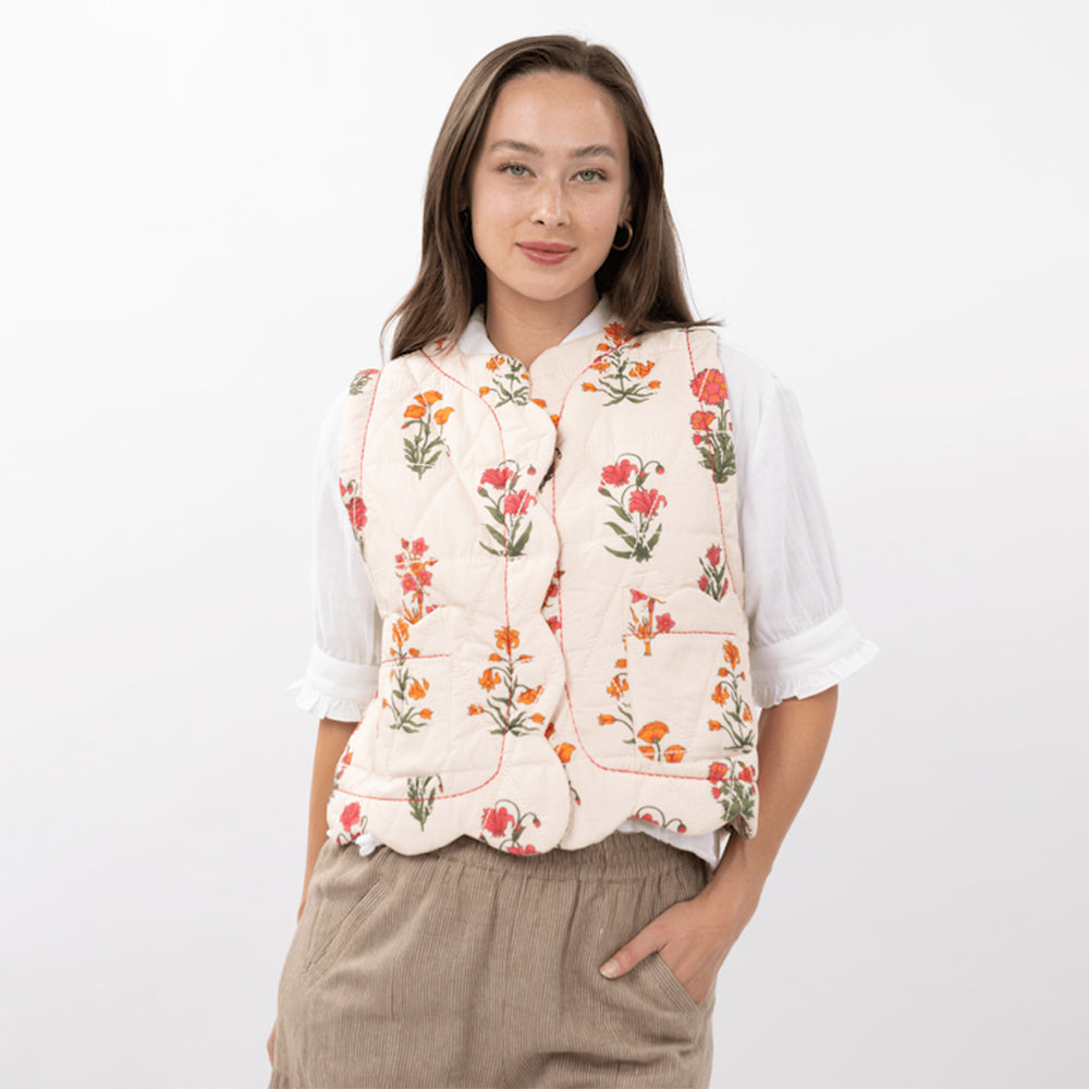 Woman wearing a floral vest over a white shirt on a white background