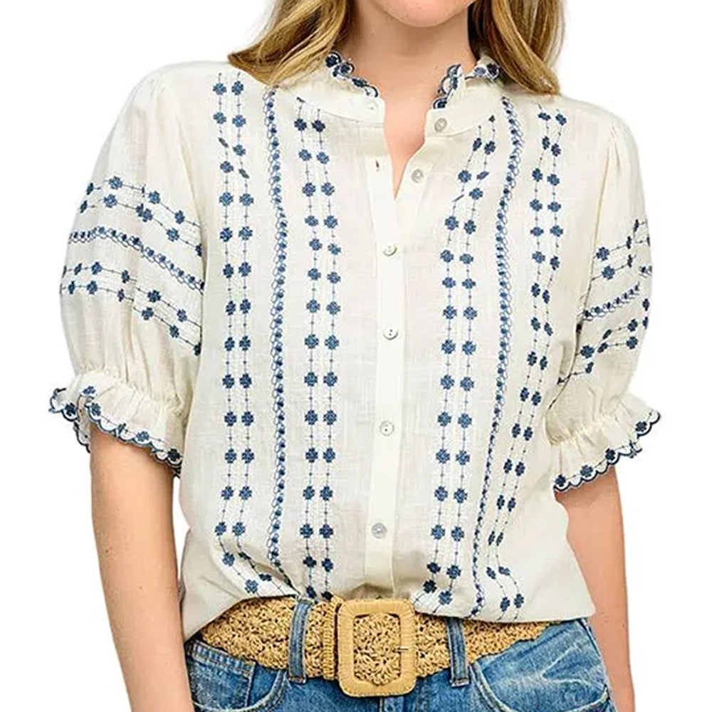 White blouse with blue floral patterns worn by a person on a white background