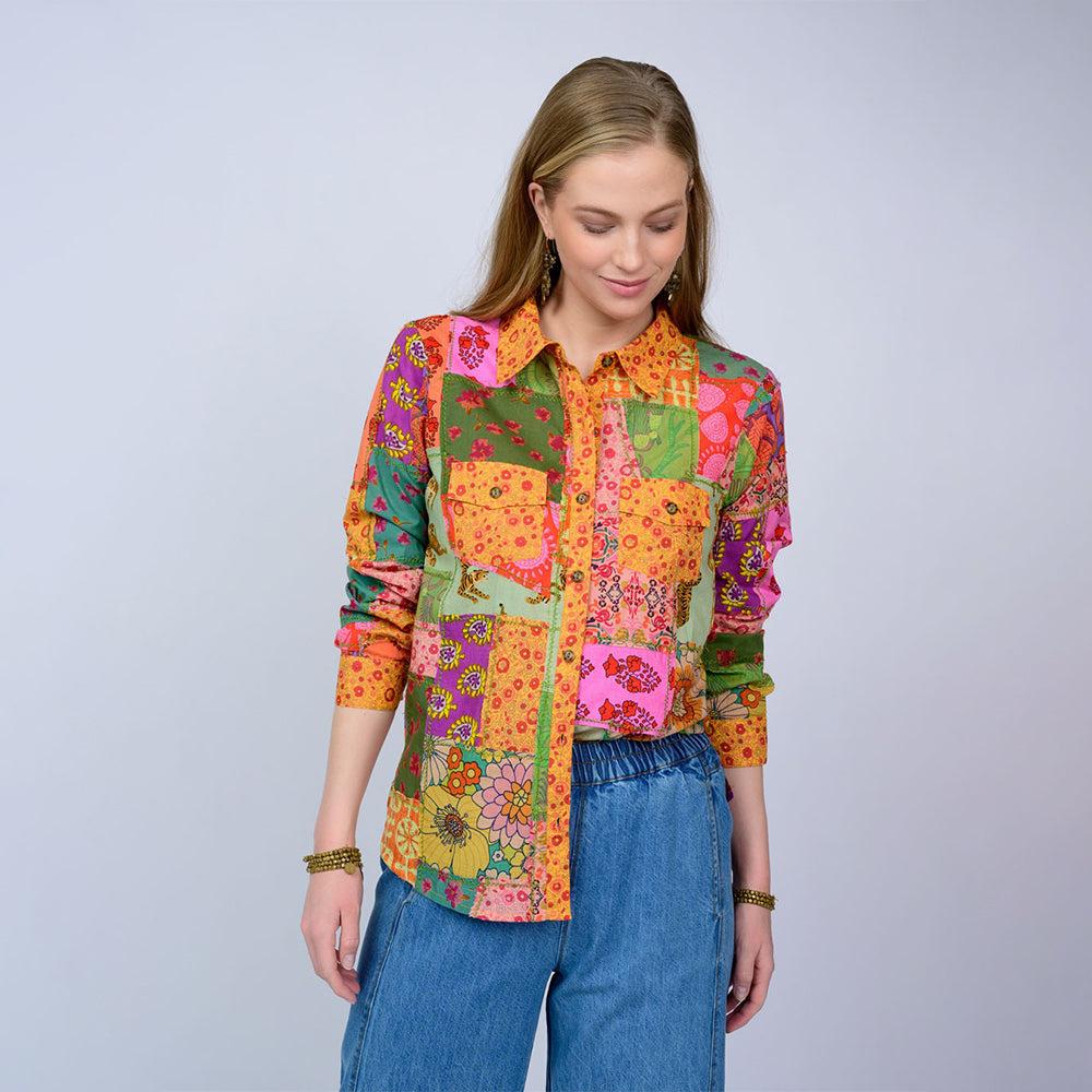 Woman wearing a colorful patchwork shirt with a plain background