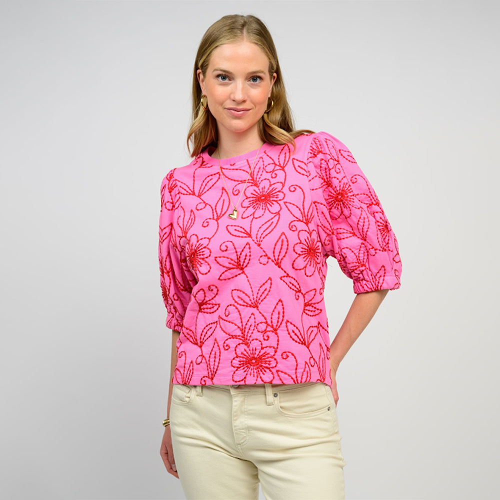 Woman wearing a pink floral blouse with a plain background