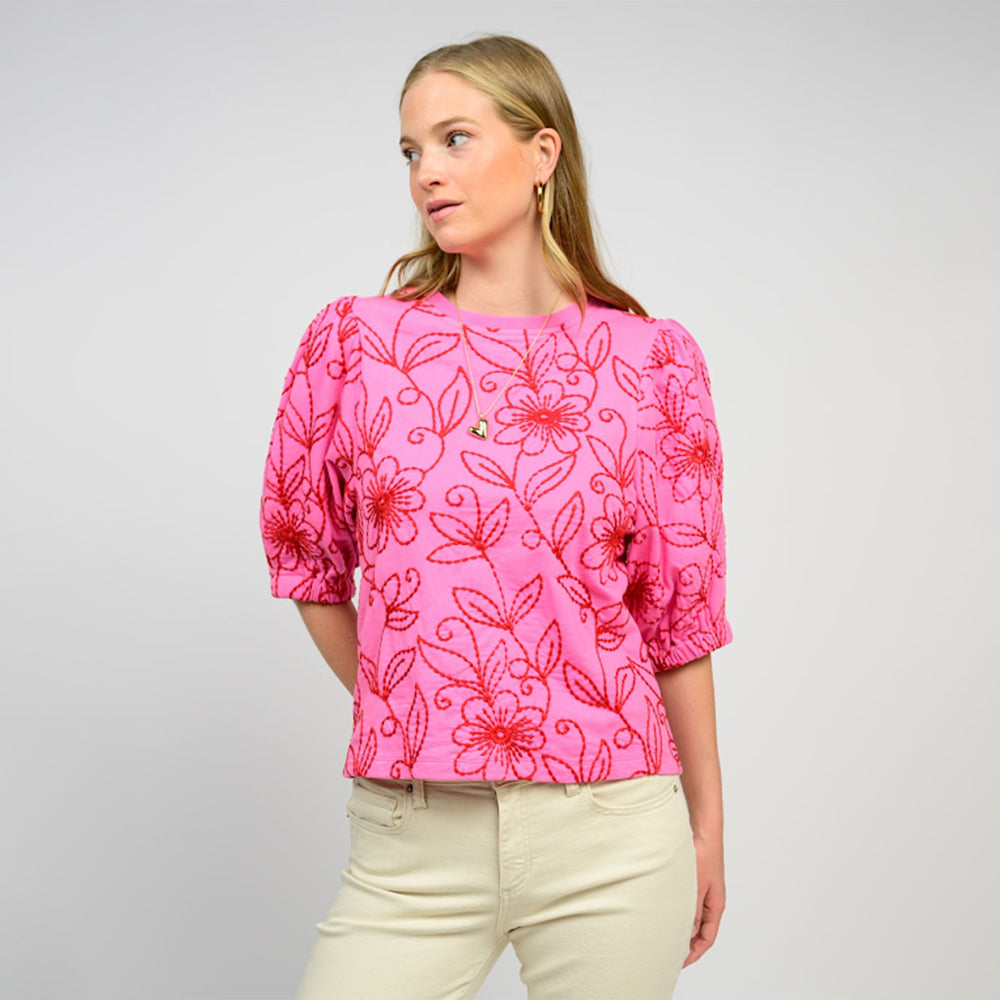 Woman wearing a pink floral blouse against a gray background