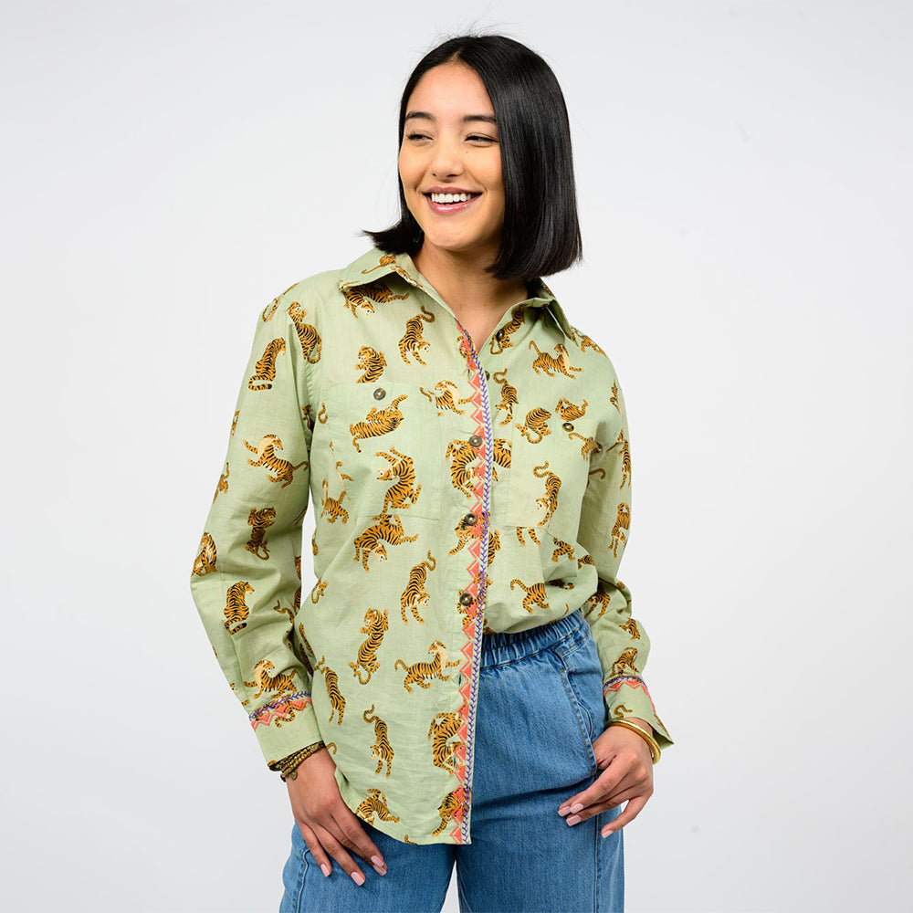 Woman wearing a light green shirt with tiger pattern and blue jeans on a white background