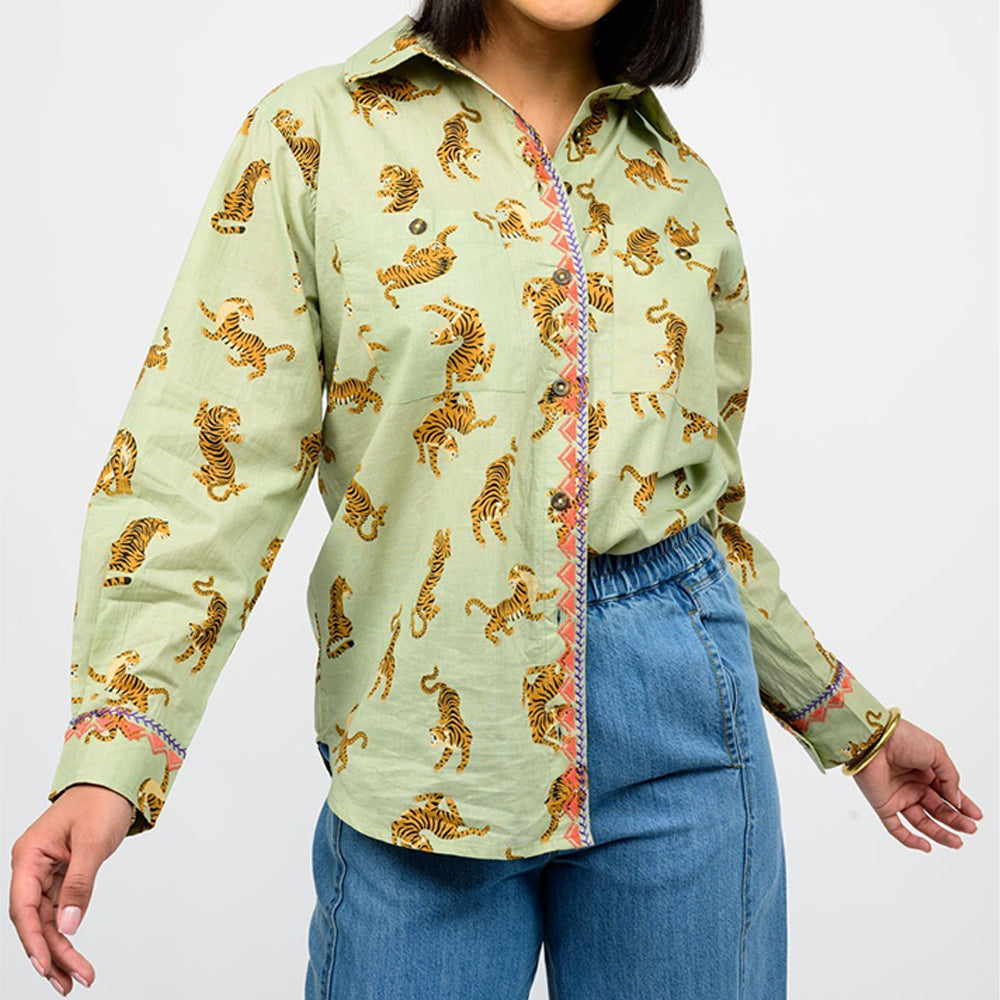 Person wearing a light green shirt with tiger pattern and blue jeans on a white background